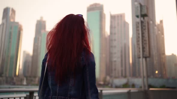 View From the Back a Woman with Red Hair is Walking in the Center of Dubai