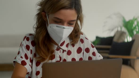 Young Woman Wears Face Mask Works Alone From Home Office Using Laptop