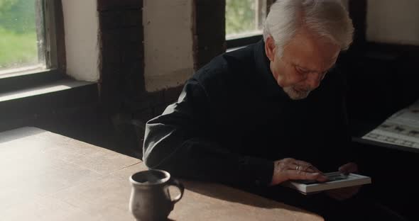 Sad Old Gray Haired Man Looks to the Portrait of Lost Close Friend