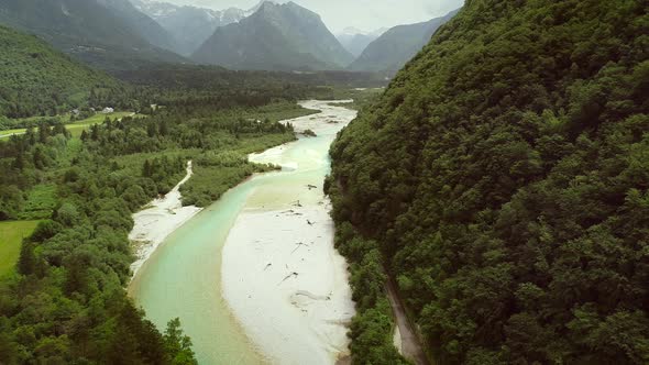 Aerial view of Soca river surrounded by many hills and vegetation in Slovenia.