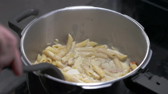 A man cooks a delicious bowl of pasta on a stovetop
