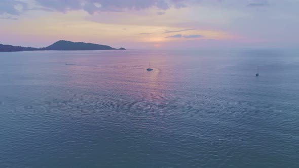 Colorful sunset above the sea surface with sail boats Aerial view drone fly over Phuket sea