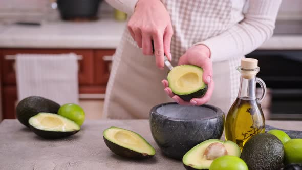 Woman Takes Out the Pulp of the Ripe Avocado From the Peel with a Spoon at Domestic Kitchen