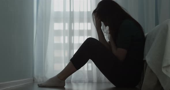 Female Sitting By The Bed On A Floor In Depression