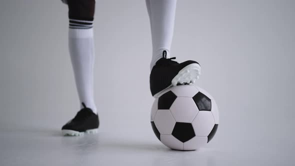 Football Ball and Legs of Football in Boots and Knee Socks in Studio Closeup View