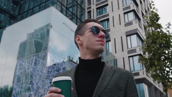 Portrait of Ambitious Businessman on Sunglasses Stand in the City Center Street and Drinking Coffee