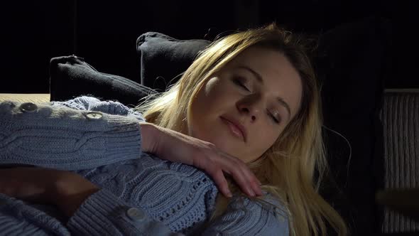 A Young Beautiful Woman Sleeps on a Couch in a Dark Room - Closeup