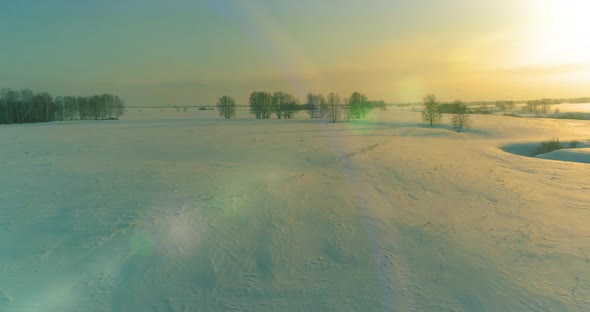 Aerial View of Cold Arctic Field Landscape Trees with Frost Snow Ice River and Sun Rays Over Horizon