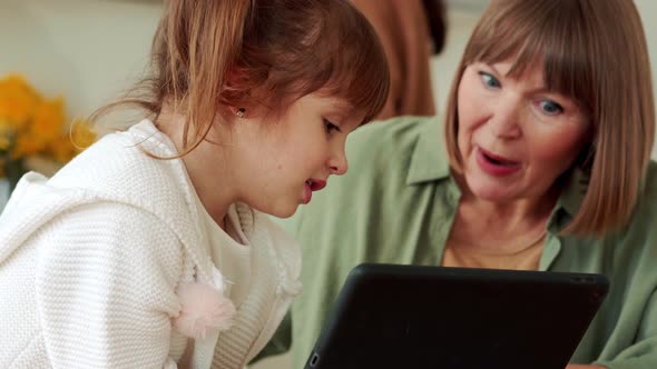 Serious grandmother and granddaughter watching something on the tablet