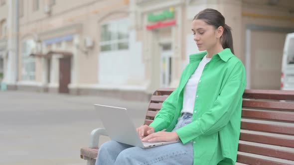 Hispanic Woman with Laptop Looking at Camera While Sitting Outdoor on Bench