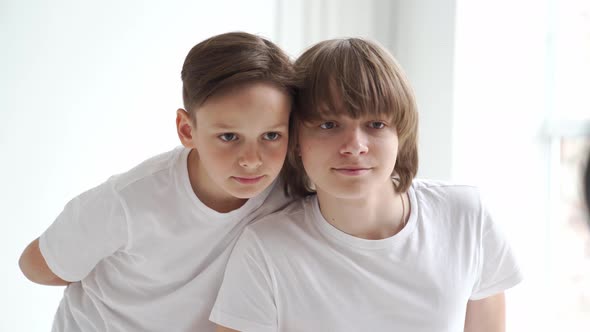 Two Boys in White Tshirts Pose for a Photographer in a Photo Studio