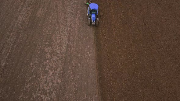 Agricultural Work in the Field, Two Blue Tractors Plow the Land