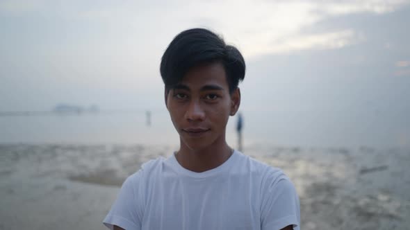 Young Thai Man Looking at Camera Smiling Standing By the Sea at Sunset  Face Closeup