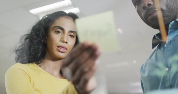 Video of focused diverse businesswoman and businessman brainstorming in office