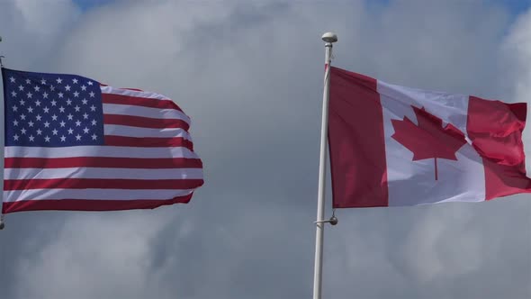 The national USA and canadian flags waving in the wind.