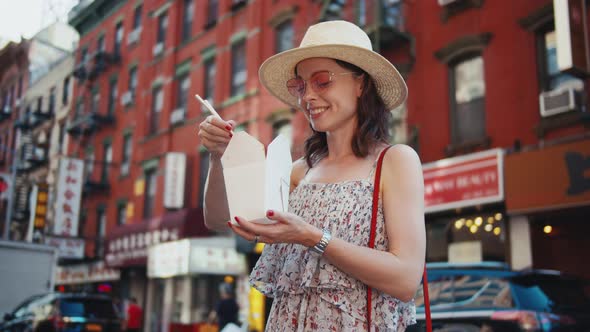 Happy girl eating Chinese food on the street in New York