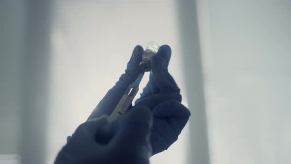 Physician Hands Filling Syringe with Antiviral Medication Holding Vial Close Up