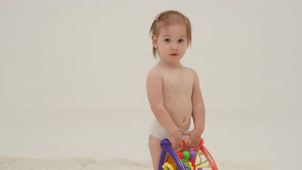 Happy Little Girl in Diaper is Playing Toys