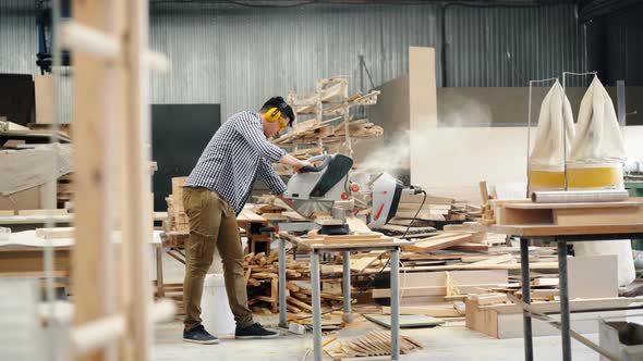 Male Worker Using Electric Saw in Wood Workshop Sawing Timber Working Alone