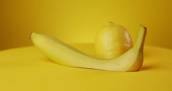 Rotating Fresh Banana and Lemon on Yellow Background