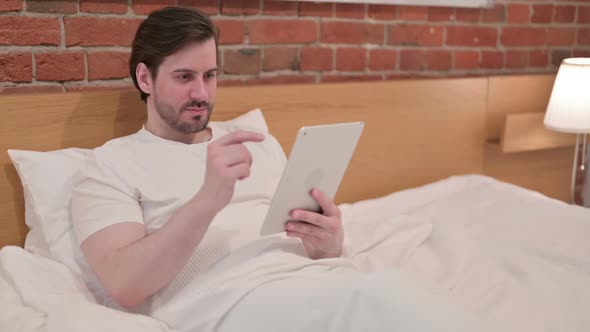 Young Businessman Using Tablet in Bed