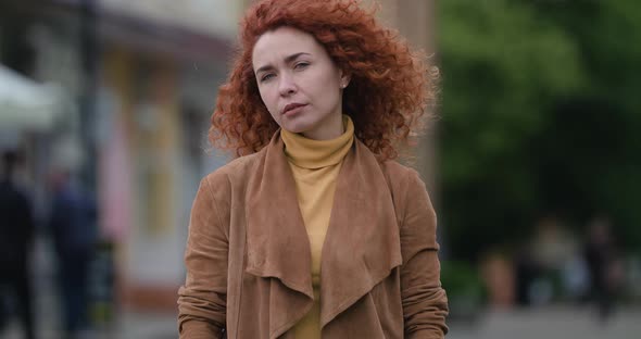 Beautiful Young Ginger Woman Close Up Looking at Camera on City Background.