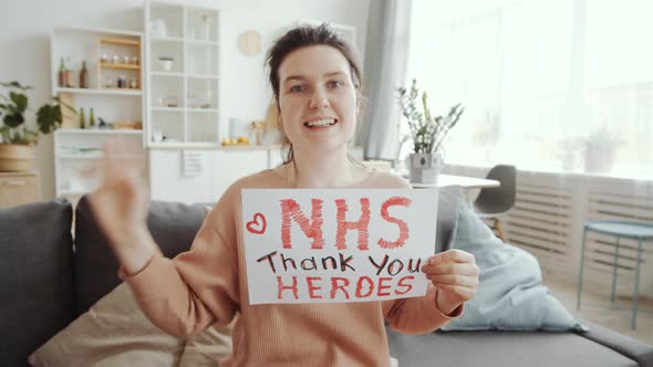 Cheerful Woman Waving and Showing «NHS thank you heroes» Inscription on Paper