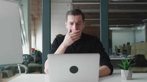 Stressed Businessman Is Shocked While Working at Laptop at Office