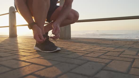 Low section of senior man tying his shoe laces