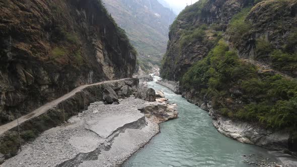 Flying through canyon over the Marsyangdi River with dirt road cut in the cliffs