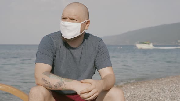 Unhappy Bold Man Close Up Portrait Wearing Medical Face Mask in Public Beach Places