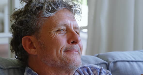 Thoughtful Senior Man Sitting on Sofa at Home 4k