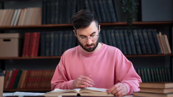 Confident Male Student Reading Vintage Paper Book Prepare to College University Exam at Library Desk