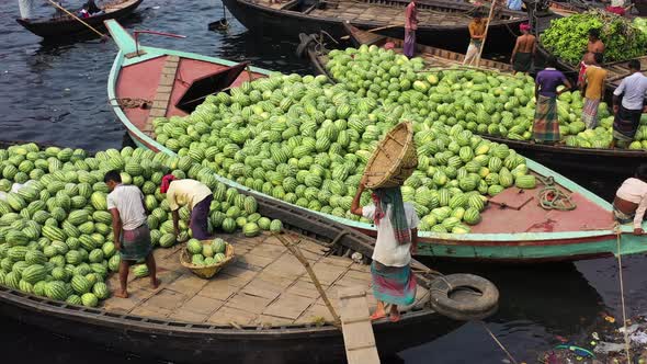 Aerial view of workers exchanging watermelons on boats along the Buriganga River.