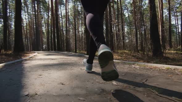 Rear view of an active sportswoman running in a city park, fashionable sports leggings, sneakers.