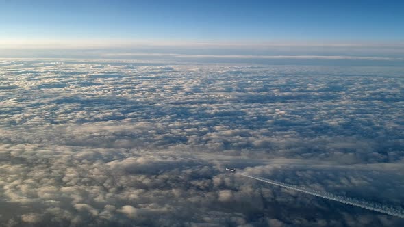 Incredible view from the cockpit of an airplane flying high above the clouds leaving a long white co