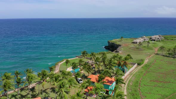 Villas on the edge of a cliff in the Caribbean, coconut trees and turquoise blue water characterize