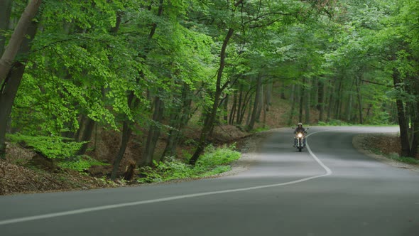 Riding a motorcycle on a road through forest