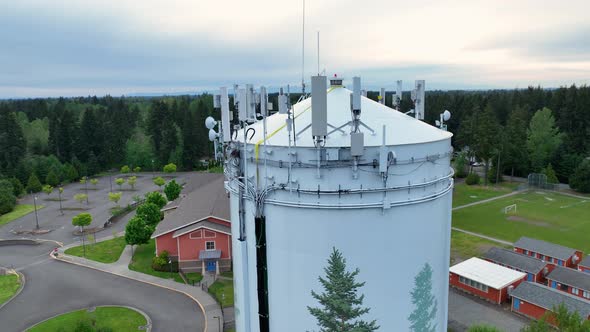 Aerial of cell tower equipment on top of a water tower at sunset.