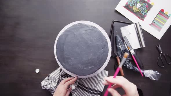 Time lapse. Step by step. Flat lay. Baker applying glittery dust with brush to a black multilayer ca