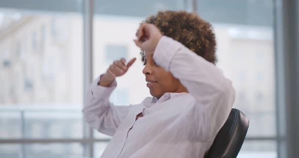 Afroamerican Businesswoman Stretching at Office Desk