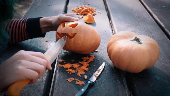 Woman carving pumpkins for Halloween on wooden table