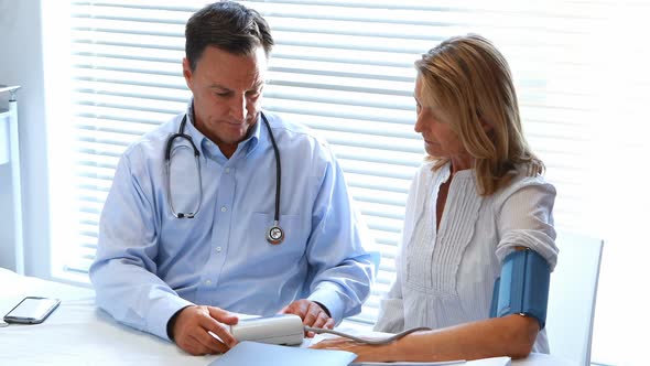 Doctor interacting with patient while checking blood pressure