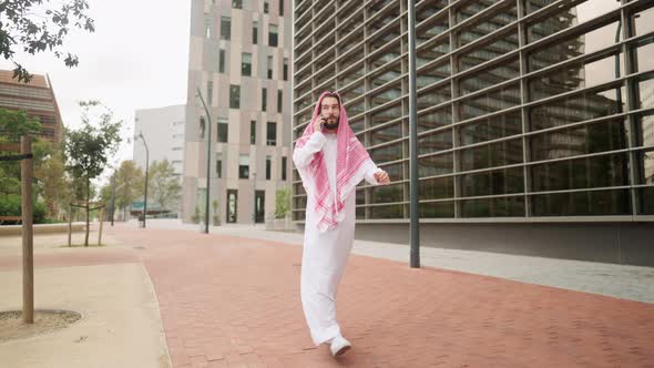 Saudi Man with Smartphone Outdoors Arab Businessman Talking on Mobile Phone While Walking on Road