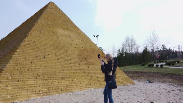 Girl Takes a Photo Near a Small Egyptian Pyramid. Park of Miniatures.