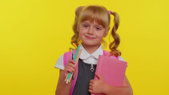 Cheerful Funny Schoolgirl Kid with Books Dressed in Uniform Wears Backpack Smiling Looking at Camera