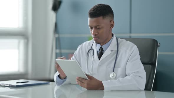 African Doctor using Tablet while Sitting in Office