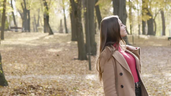 Young Girl Looking Around and at Camera with Joy in Sunny Autumn Park on a Walk