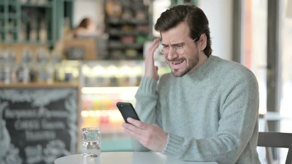 Young Man Reacting Loss While Using Smartphone