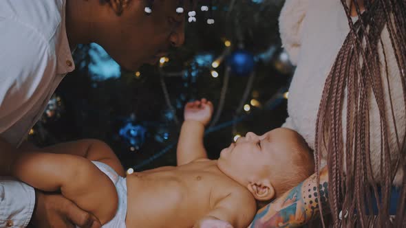 African American Parents Holding Newborn Baby in Front of the Christmas Tree